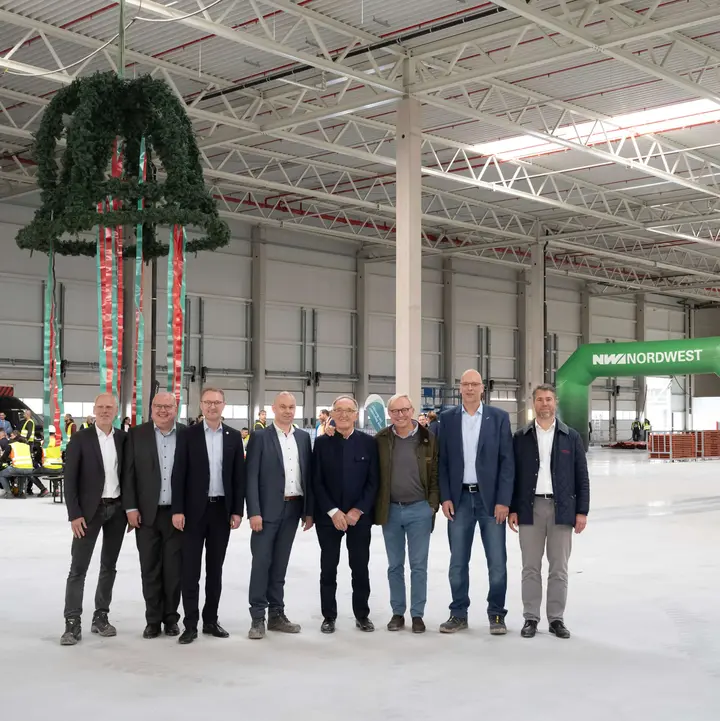 Offizielle vor dem Richtkranz in einer Halle des neuen Zentrallagers