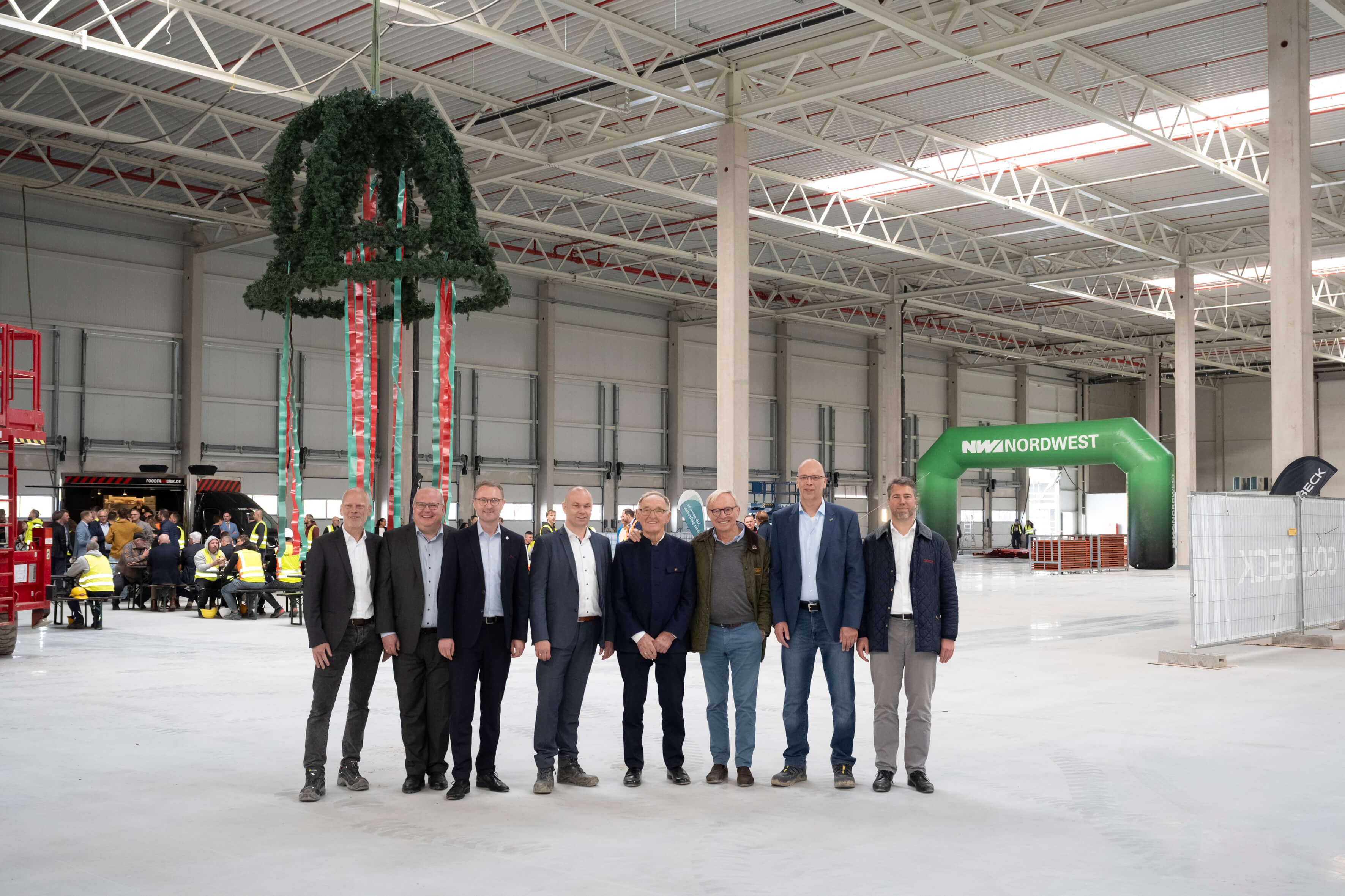 Offizielle vor dem Richtkranz in einer Halle des neuen Zentrallagers
